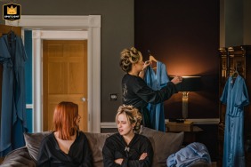 At Grassfield Hall in Harrogate, Yorkshire, UK, bridesmaids prepare for the wedding, surrounded by their elegant dresses. The candid scene captures joy, excitement, and friendship during this special getting ready moment.